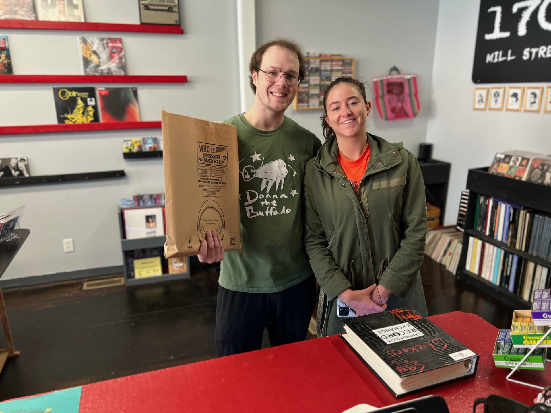 Record store staff holding a printed kraft bag behind the counter